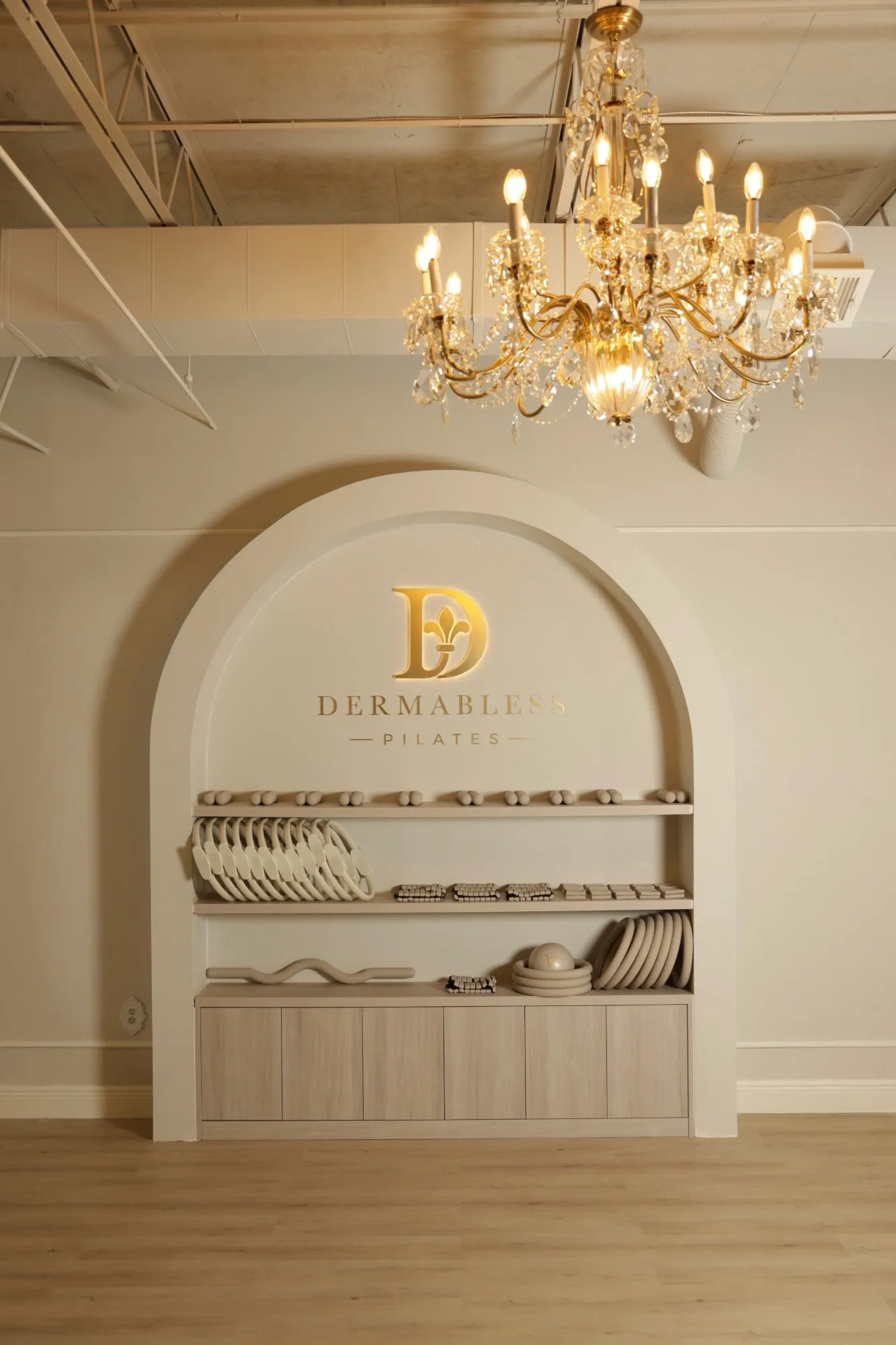 The arched niche of the Dermabless Pilates studio with the illuminated gold monogram.